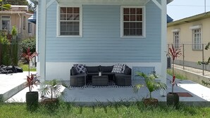 Ein Haus mit überdachter Veranda, zwei Fenstern und einer Sitzecke mit Sofa und Couchtisch.
