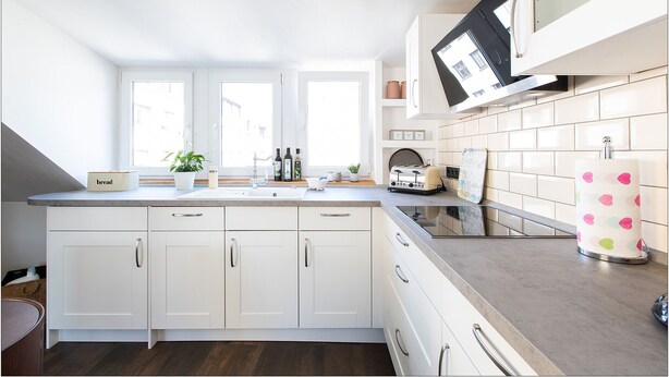 A modern kitchen with white cabinets, a large window, and a microwave.