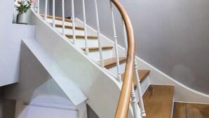 A spiral staircase with white railings and wooden steps, leading to an upper floor.
