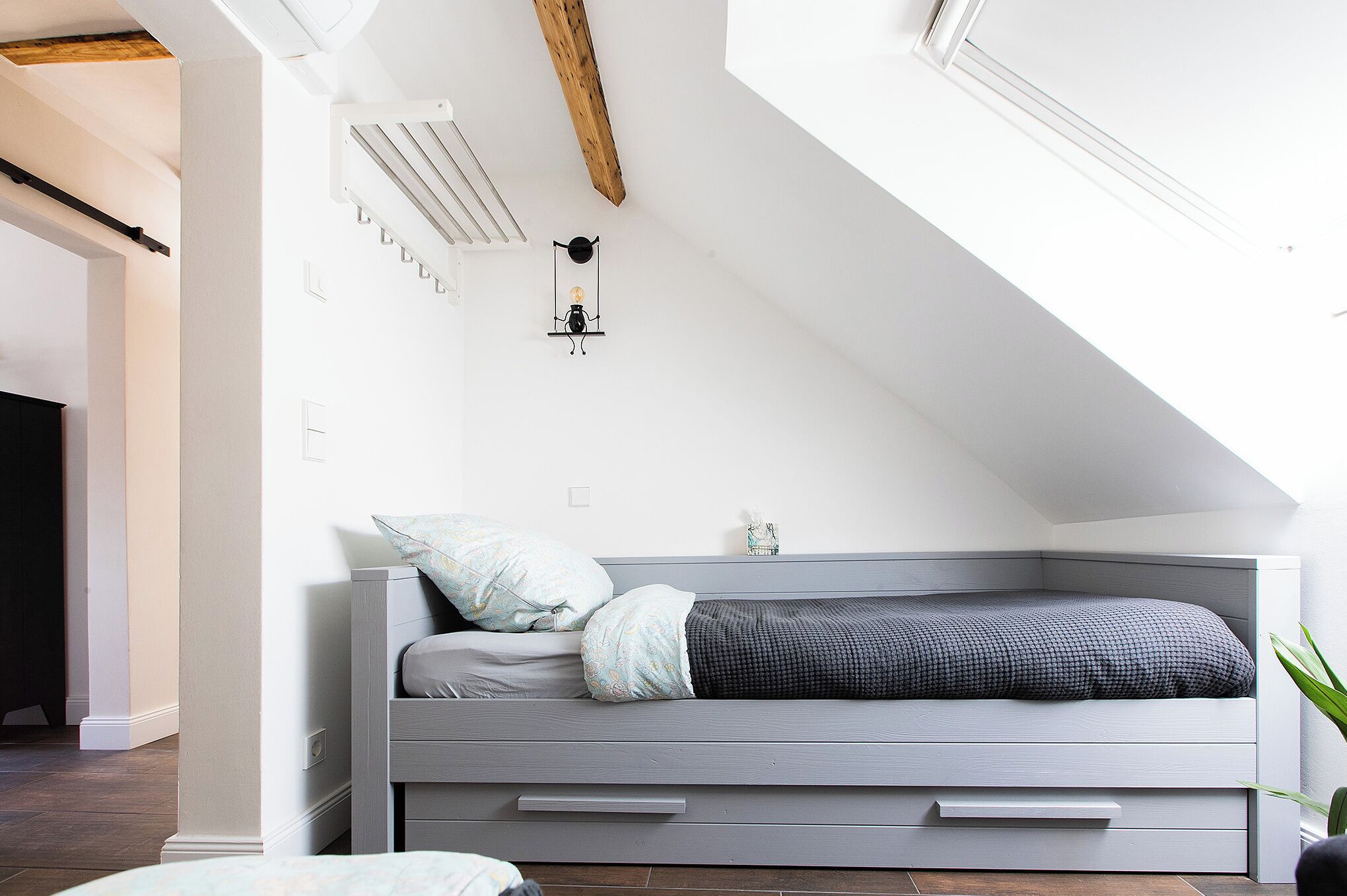 A modern loft bedroom with a built-in bed, a small bedside table, and a wall-mounted light fixture.