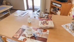 Une table à manger avec des sets de table décorés de motifs représentant du café et des pâtisseries, une tasse de café et une bouteille d’eau.
