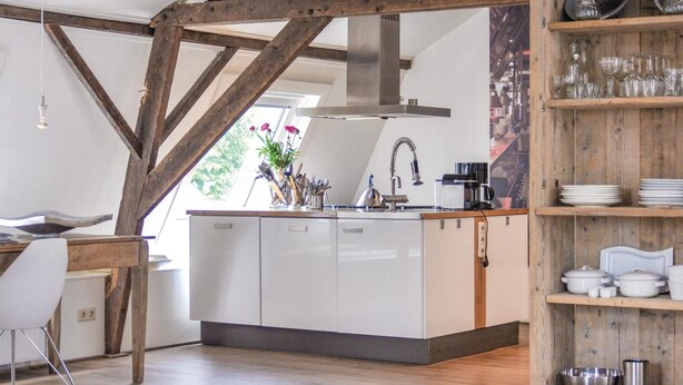 A modern kitchen with a central island, wooden beams, and a view of the outdoors. - 3 bedroom pet friendly home in Leende (Leende)
