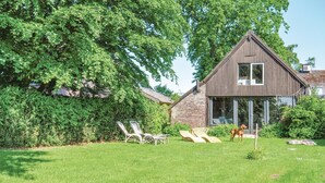 A modern house with a large tree, a patio with chairs, and a dog. - 3 bedroom pet friendly home in Leende (Leende)