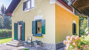 A yellow building with green shutters, a small table, and steps leading to the entrance.