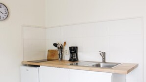 Una cocina compacta con un lavamanos, una cafetera y un reloj en la pared.