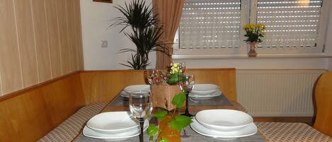 A dining table set with white plates, wine glasses, and a centerpiece of flowers and greenery.