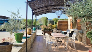 An outdoor patio with a table and chairs, surrounded by potted plants and a pergola. - 2 bedroom beautiful home in Gordes (Gordes)