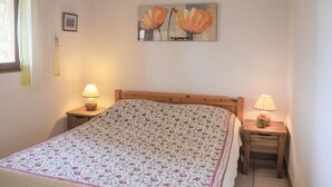 A bedroom with a wooden bed, floral bedding, two bedside lamps, and a painting of flowers on the wall. - 2 bedroom beautiful home in Gordes (Gordes)