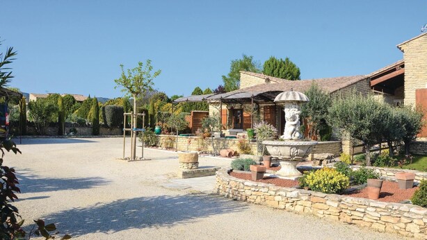 A courtyard with a stone fountain, potted plants, and a pergola. - 2 bedroom beautiful home in Gordes (Gordes)