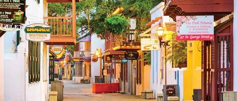 A street lined with shops and restaurants, including a boutique and a cafe.