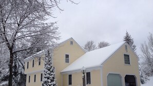 A two-story house with a garage, surrounded by snow-covered trees and a snow-covered lawn. - Wachusett Mountain Getaway, Lake Adjacent Home! Near 1761 Old Mill and Trails! (Westminster)