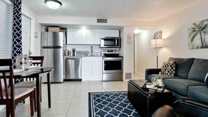 A modern kitchen with stainless steel appliances, a dining area with a table and chairs, and a living room with a sofa and a coffee table. - Bay Waterfront Mermaid's Retreat Delights! Great suite on desirable Manasota Key! (Englewood)