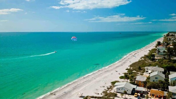 A coastal beach scene with a clear sky, a sandy beach, and a few buildings along the shore. - Bay Waterfront Mermaid's Retreat Delights! Great suite on desirable Manasota Key! (Englewood)