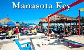 A beachside restaurant and tiki bar named 'Manasota Key' with outdoor seating and umbrellas. - Bay Waterfront Mermaid's Retreat Delights! Great suite on desirable Manasota Key! (Englewood)
