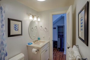 A bathroom with a sink, mirror, towel rack, and framed artwork.