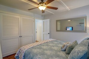 A bedroom with a bed, a ceiling fan, a TV, and a wardrobe.