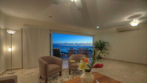 A living room with a view of the ocean, a wooden coffee table, two armchairs, and a vase with flowers. - Farito Beachfront Penthouse, Surf & Paddle Board. (Punta de Mita)