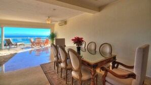 A dining area with a glass table and chairs, a potted plant, and a view of the ocean. - Farito Beachfront Penthouse, Surf & Paddle Board. (Punta de Mita)