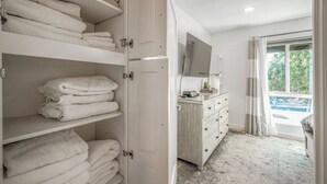 Et hotelværelse med walk-in-skab, et sminkebord med spejl og udsigt til en pool.