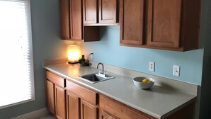 A kitchen with wooden cabinets, a countertop, a sink, and a lit lamp. - Intimate low country Carriage House with gorgeous appointments! (Bluffton)