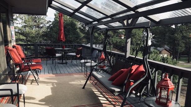 A covered outdoor deck with seating, a table, and a hanging lantern. - PACK YOUR BAGS & LET THE ADVENTURES BEGIN! SLEEPS 10, HOT TUB, & PET FRIENDLY (Pagosa Springs)