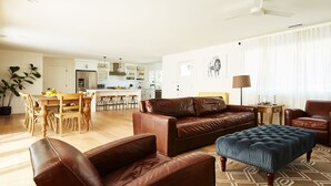 A spacious living area with a brown leather sofa, a blue ottoman, and a dining table with chairs. - Modern Sonoma Farmhouse, Hot Tub, Close to Historic Sonoma  Square (Sonoma)