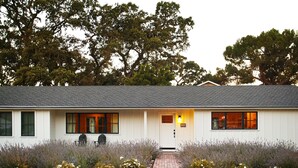 A white building with a gray roof, a brick pathway leading to the entrance, and a row of lavender plants in front. - Modern Sonoma Farmhouse, Hot Tub, Close to Historic Sonoma  Square (Sonoma)