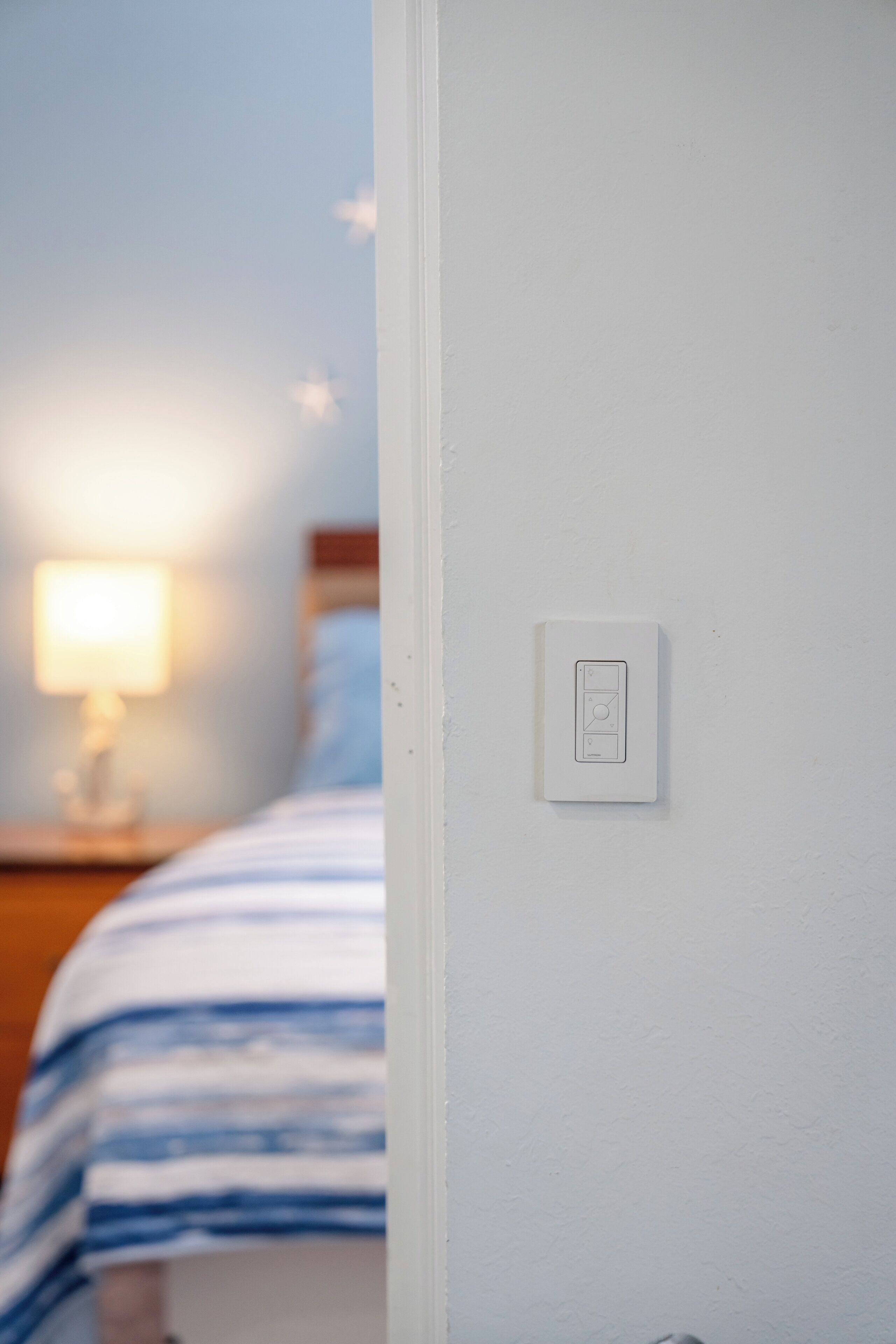 A bedroom with a bed, a nightstand, and a wall-mounted light switch.