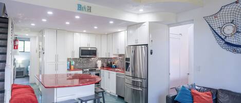 A modern kitchen with white cabinets, stainless steel appliances, and a central island with stools.