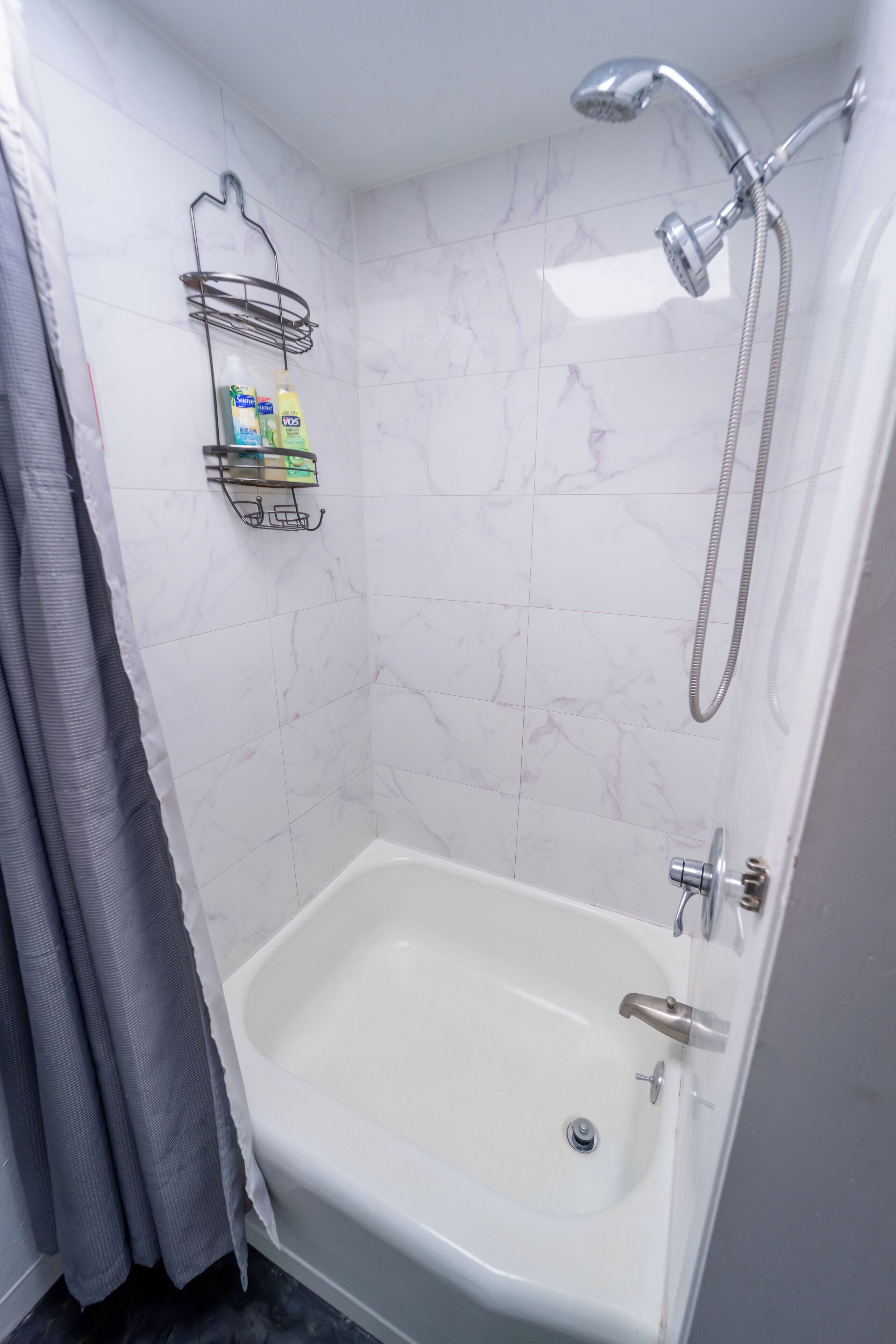 A bathroom with a bathtub, a shower, and a towel rack with toiletries.