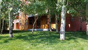A building with a red facade, surrounded by a well-maintained grassy area with birch trees. - Enjoy Our Mountain Retreat in The Teton Valley adjacent to Jackson Hole (Victor)