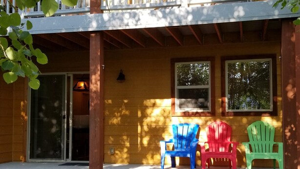 A porch with wooden beams, a sliding glass door, and three colorful Adirondack chairs. - Enjoy Our Mountain Retreat in The Teton Valley adjacent to Jackson Hole (Victor)