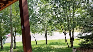 A grassy area with trees and a wooden deck. - Enjoy Our Mountain Retreat in The Teton Valley adjacent to Jackson Hole (Victor)