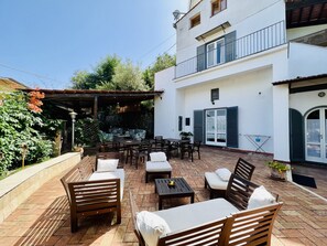 Eine Terrasse mit Sitzgelegenheiten, einer Pergola und einer Steinmauer.