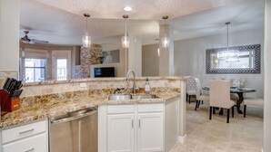 A modern kitchen with granite countertops, white cabinetry, and pendant lighting. - Luxury Living in Kierland Greens (Scottsdale)