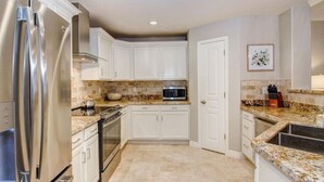 A modern kitchen with white cabinets, stainless steel appliances, granite countertops, and a tiled backsplash. - Luxury Living in Kierland Greens (Scottsdale)