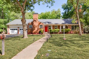 A two-story brick house with a red front door, a garage, and a well-maintained lawn.