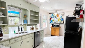 A kitchen with a dishwasher, a microwave, a black refrigerator, and a wooden cabinet. - Cheerful Home W/ Private 15' Swim Spa, Big Fenced Yard, & Fire Pit (Arlington)