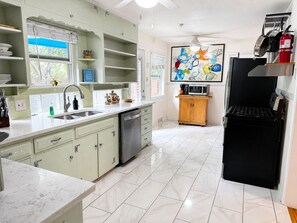 A kitchen with a dishwasher, a microwave, a black refrigerator, and a wooden cabinet.