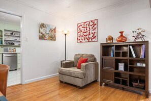 A living room with a sofa, a bookshelf, a painting, and a lamp. - Cheerful Home W/ Private 15' Swim Spa, Big Fenced Yard, & Fire Pit (Arlington)