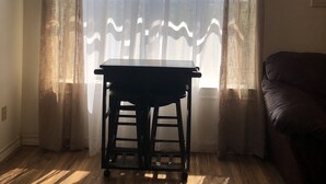 Une pièce avec un plancher en bois, une table et un canapé de couleur sombre.