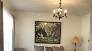 Une chambre à coucher avec un lit, une chaise, une table de chevet, une lampe et un tableau au mur.
