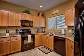 A kitchen with wooden cabinets, a stove, microwave, sink, and refrigerator. - Next to Golf, Prime Location, Heated Pool & Spa, Upgraded Unit, BBQ, and More! (Scottsdale)