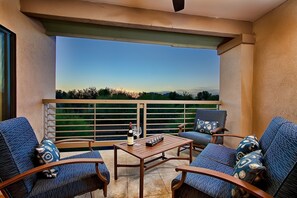 A balcony with a wooden table, two blue patterned sofas, and a bottle of wine. - Next to Golf, Prime Location, Heated Pool & Spa, Upgraded Unit, BBQ, and More! (Scottsdale)