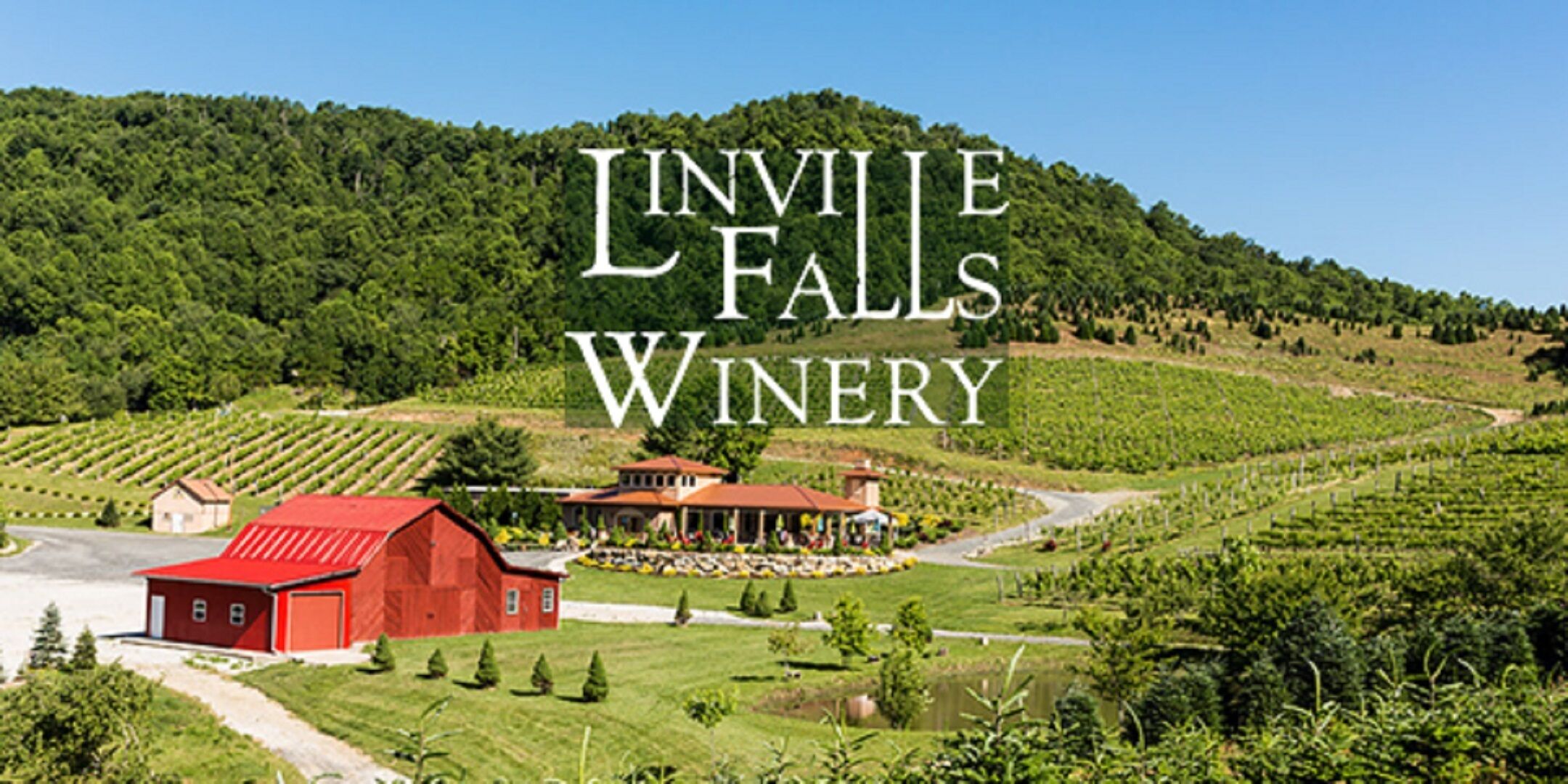 Un paysage de vignoble avec une grange rouge et un bâtiment portant l’inscription « Invilve Falls Winery ».