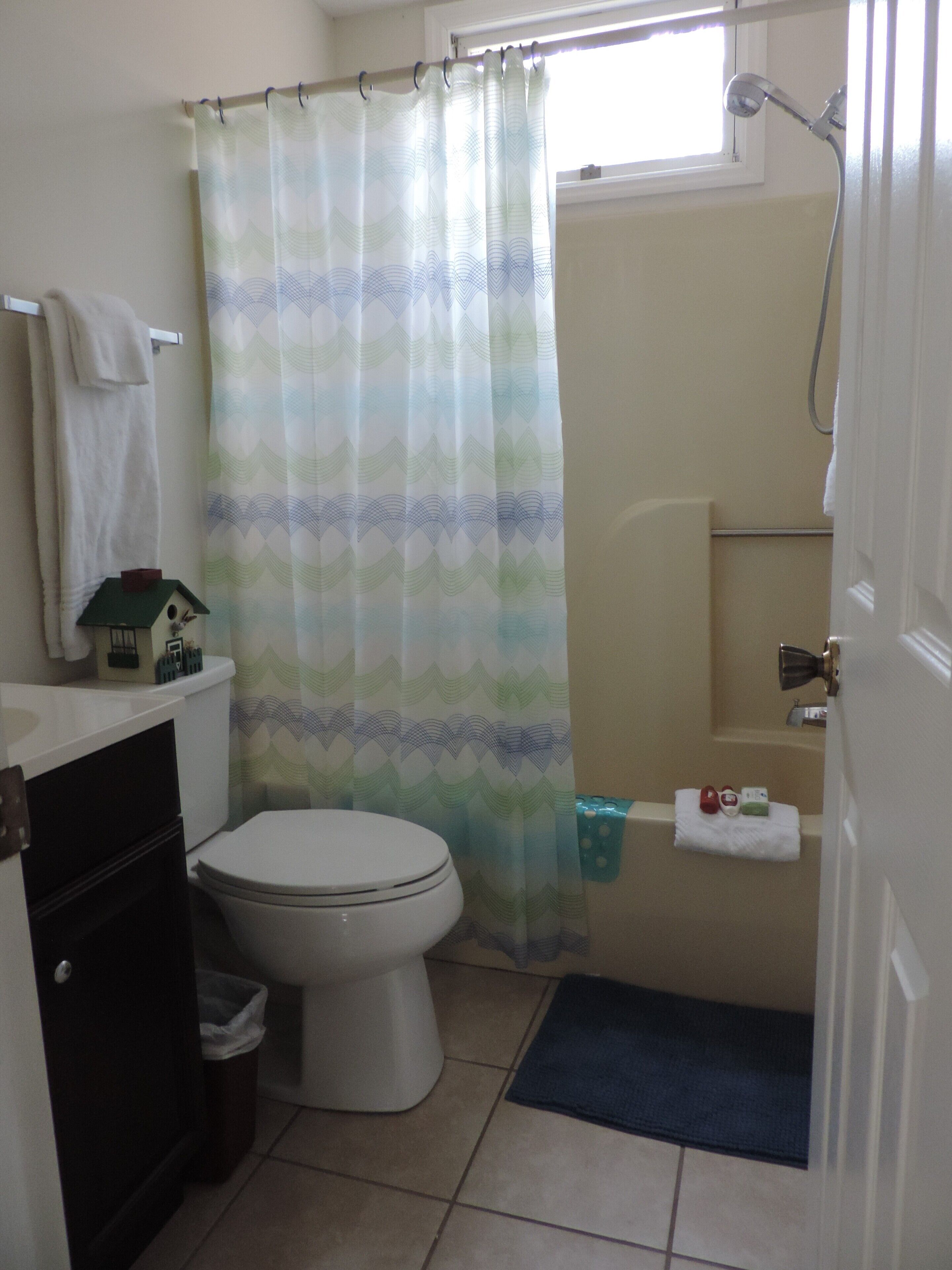 Une salle de bain équipée de toilettes, d’une douche, d’un porte-serviettes et d’une petite nichoir posé sur le lavabo.