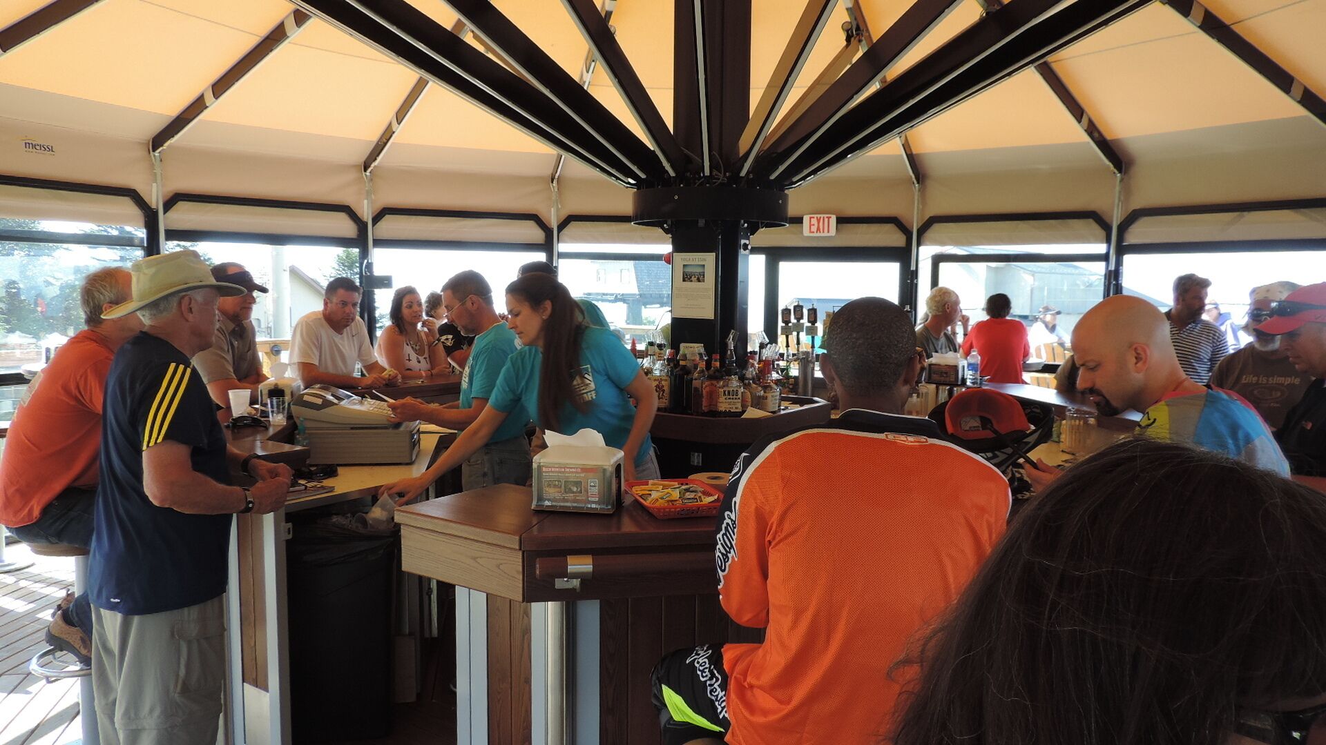 An indoor bar area with a counter, bar stools, and a variety of bottles on the shelves.
