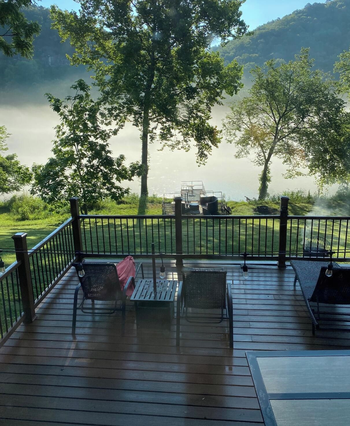 Une terrasse avec des sièges extérieurs, offrant une vue sur un plan d’eau et des arbres.