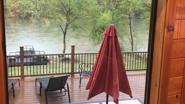 Une terrasse en bois avec des meubles d’extérieur, notamment une table et des chaises, ainsi qu’un parasol rouge.