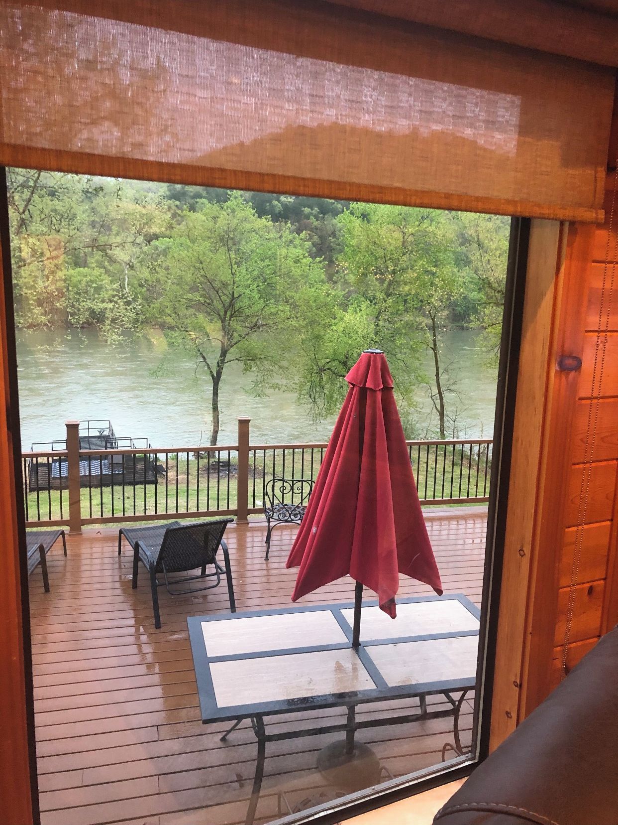 A wooden deck with outdoor furniture, including a table and chairs, and a red umbrella.